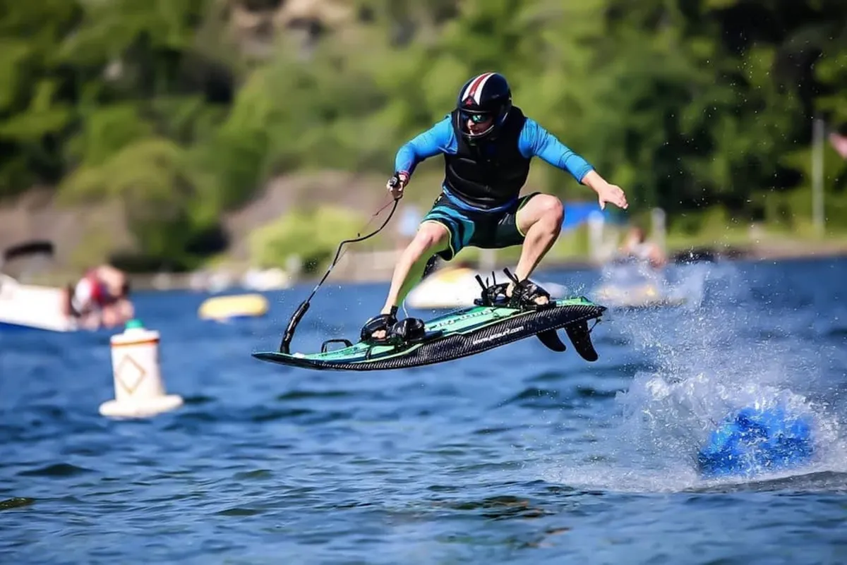 This dynamic image features a person wakeboarding, sending up splashes of water, with surrounding boats and open lake in view. The scene is energetic and adventurous, capturing the thrill of watersports and family fun on the water—a core aspect of the marina experience described in the section.