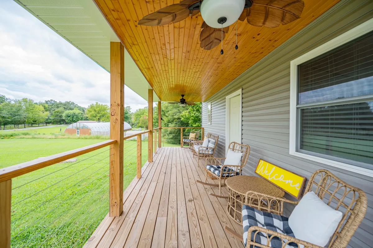 An exterior view of the wooden porch, featuring rattan chairs and a warm welcome sign. The space invites relaxation, fresh air, and inspiration from the surrounding countryside—perfect for breaks between work sessions.